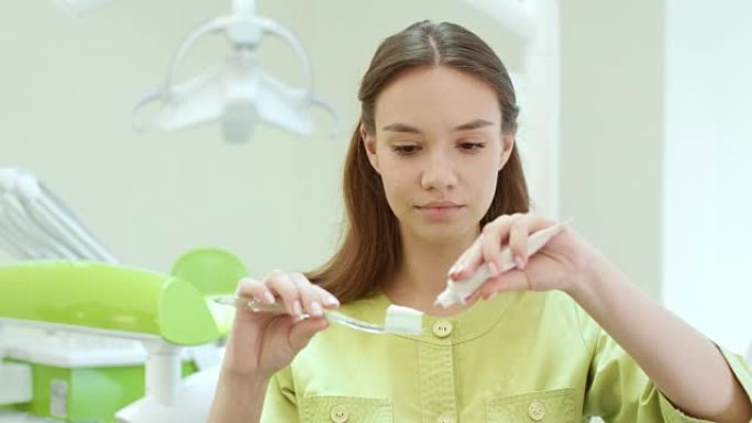 漂亮的女孩在牙刷上挤牙膏。口腔科助理