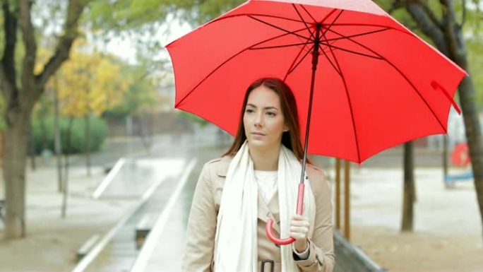 严肃的女人在公园的雨中行走