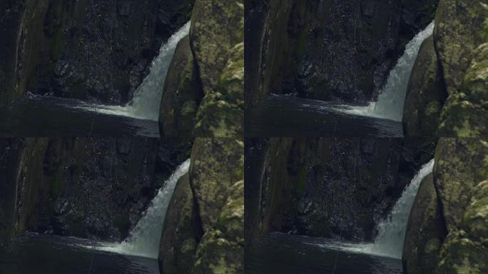 从山上的瀑布流出的河水在河里的大石头上流动。瀑布梯级中的流山河