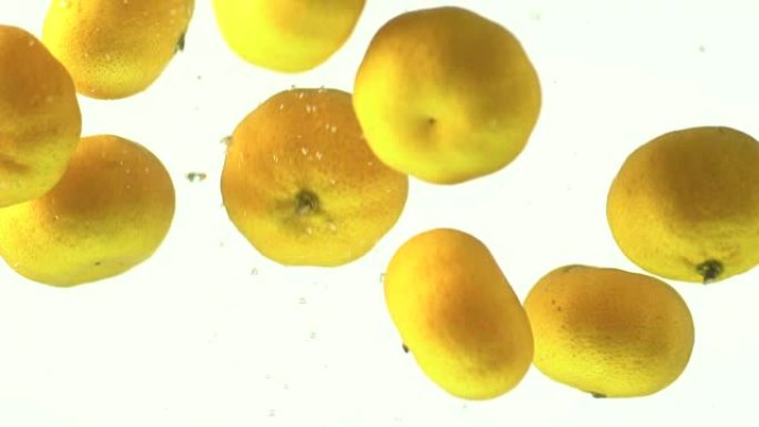 掉落或掉落的小橙色水果在白色背景上滴在水中