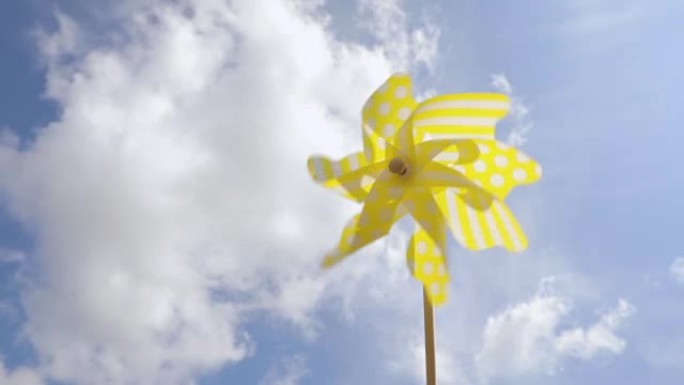 黄色风车在蓝天上随风旋转。夏季概念