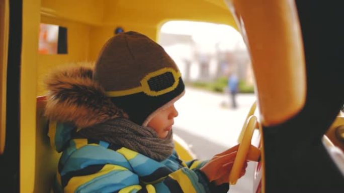 这个男孩戴着头盔在旋转木马上骑玩具车