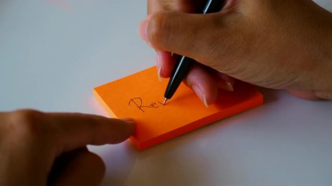 在橙色的便签纸或记事本纸上手写 “记住” 一词。运动4k镜头