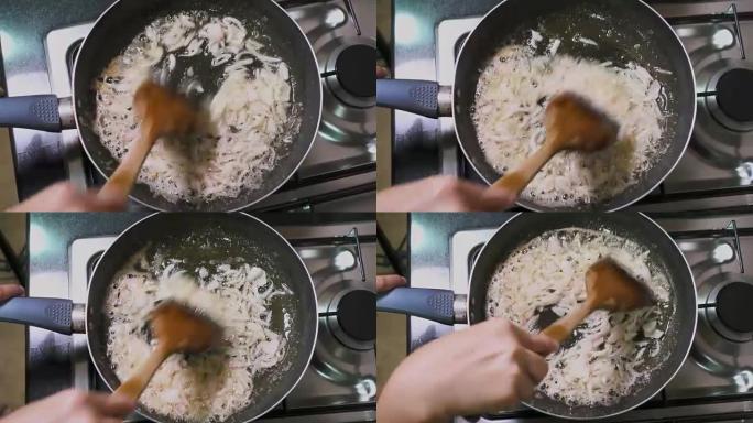 女人的俯视图在家里的厨房的燃气灶上，在锅里用油煎炸洋葱片。烹饪食物。