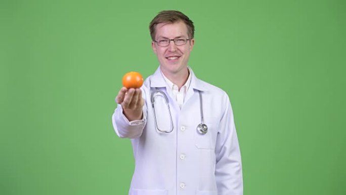 拿着橙色水果的年轻人医生的肖像