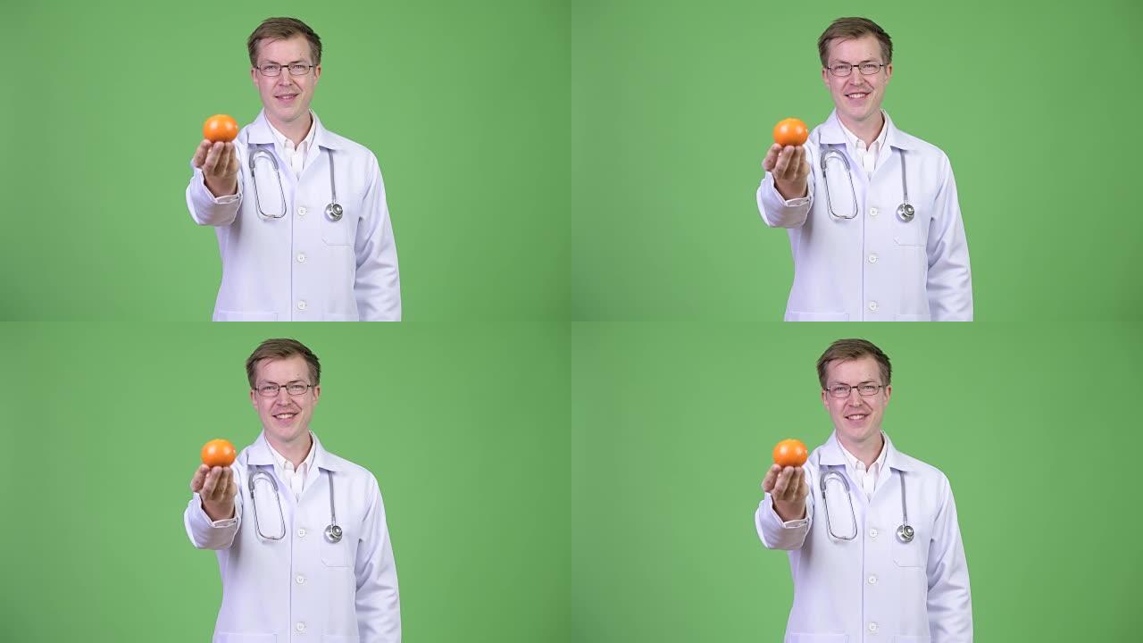 拿着橙色水果的年轻人医生的肖像