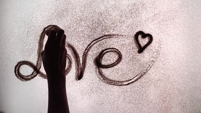 艺术家用沙子画了爱这个词。沙动画。沙子爱情上的铭文