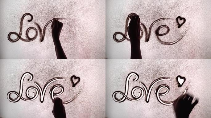 艺术家用沙子画了爱这个词。沙动画。沙子爱情上的铭文