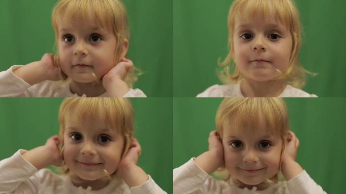 快乐的三岁女孩纠正发型。可爱的金发孩子。棕色的眼睛。绿屏