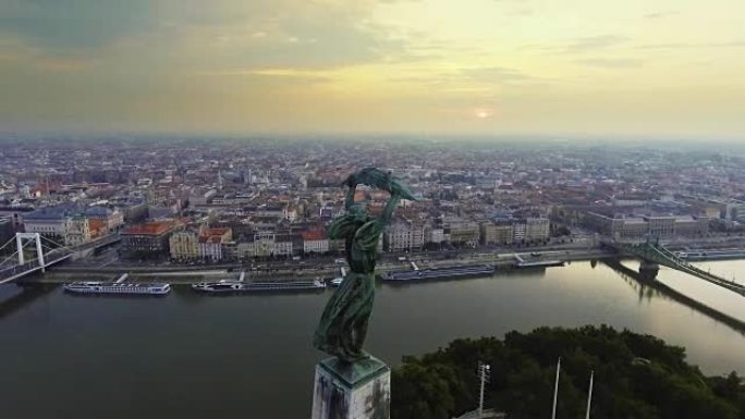 在自由女神像周围飞行，背景是布达佩斯的天际线。匈牙利布达佩斯——日出时的4K航拍画面