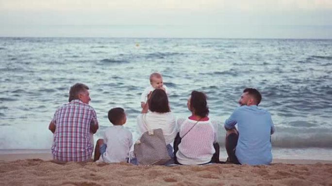坐在海滩上欣赏海景的友好大家庭