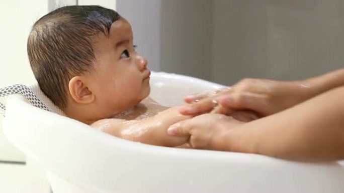 亚洲婴儿在浴缸中洗澡，母亲为幼儿提供卫生和护理