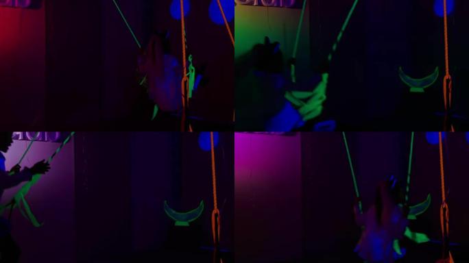 小女孩在超滤光灯下的黑暗房间里玩霓虹灯秋千