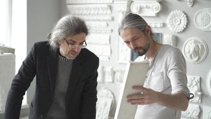 两位成熟的男性室内设计师讨论白色石膏