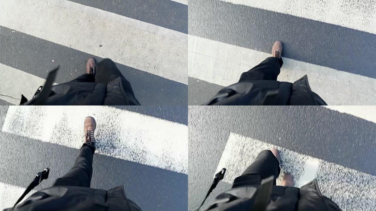 走在人行横道斑马线上的人的视点。慢动作中人靴的观点
