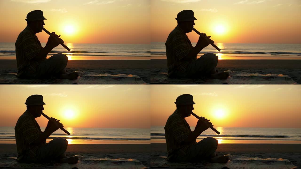 日落时在沙滩上演奏竹笛的老人剪影