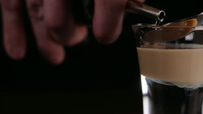 酒保在餐厅制作酒精鸡尾酒。专家酒保正在夜总会添加配料鸡尾酒。特写