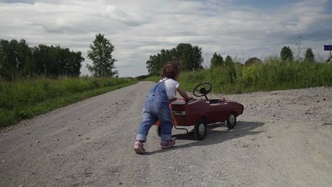 一个小女孩在路上推着她的大玩具车