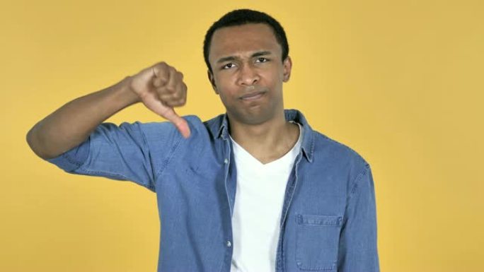 年轻的非洲男子在黄色背景上示意拇指朝下