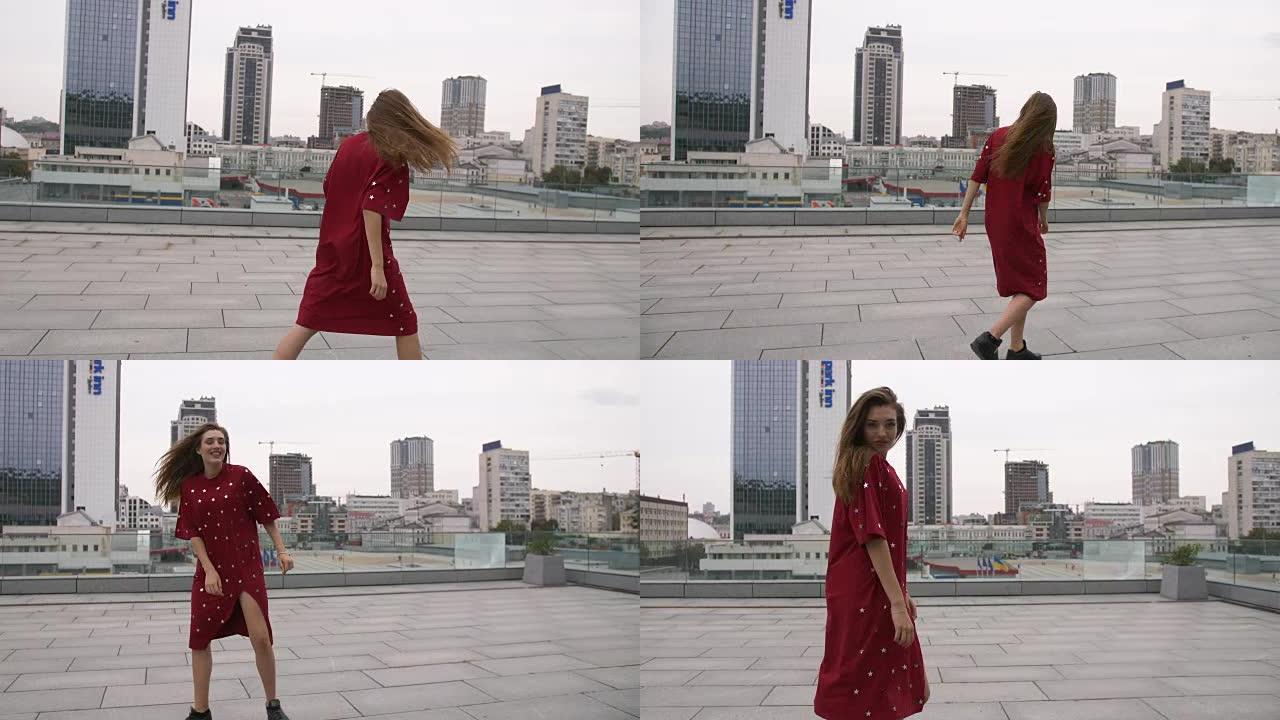 穿着红色连衣裙的迷人女孩走在城市的街道上