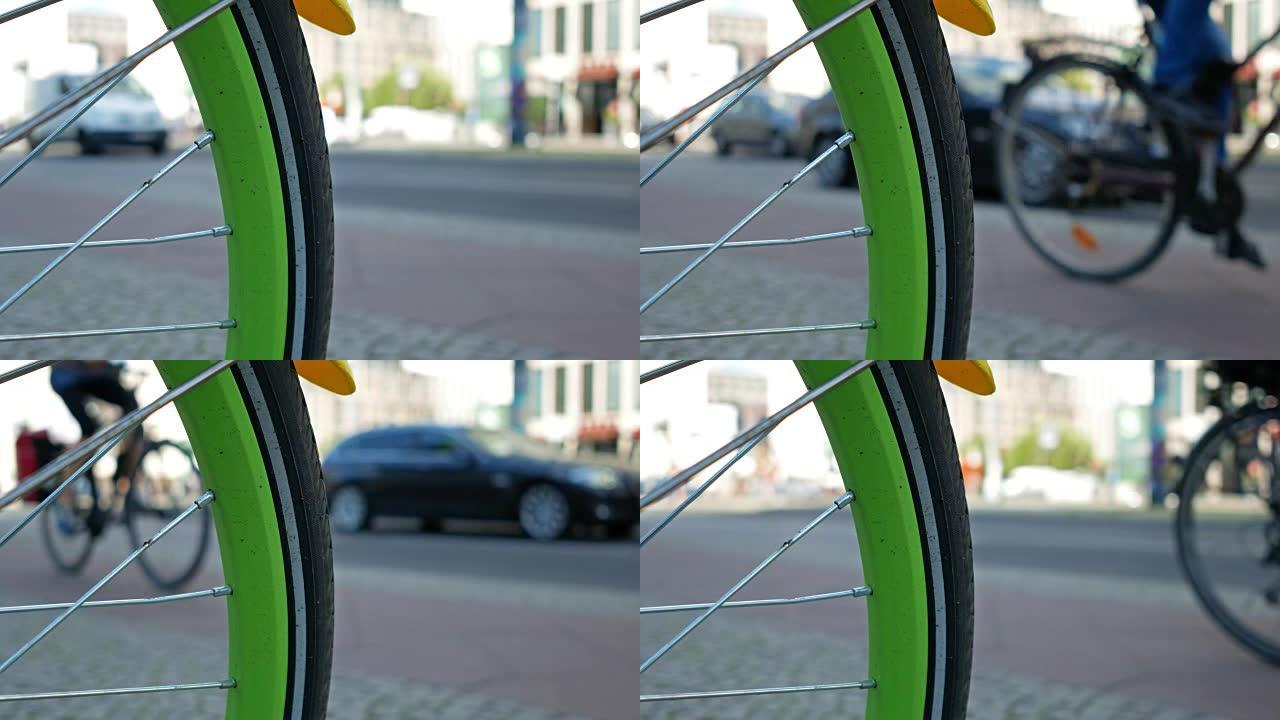 背景中有交通和骑自行车者的自行车车轮，选定焦点