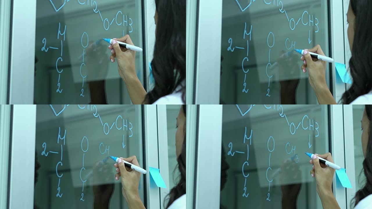 科学家在现代实验室或医学中心的玻璃墙上写分子式。科学、测试开发和实验室行业的概念。
