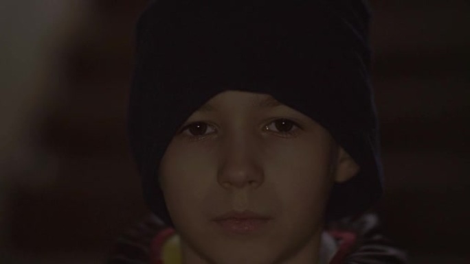 无家可归的少年男孩独自站着看着镜头，脸上疼痛，天气寒冷