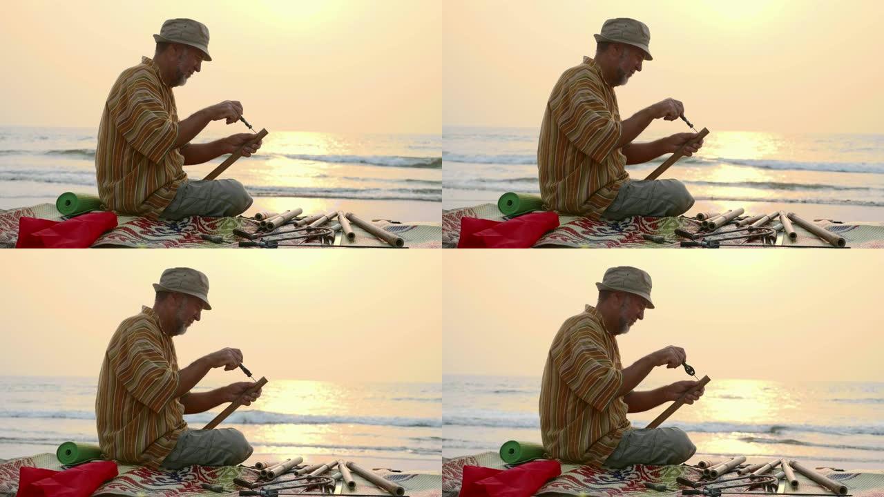 高年级男子坐在沙滩上，用手制作长笛。
