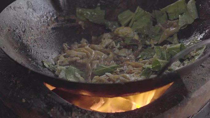 一个男人用炭炉做饭的电影镜头。用明火做的炒锅面条。泰国曼谷唐人街的街头美食