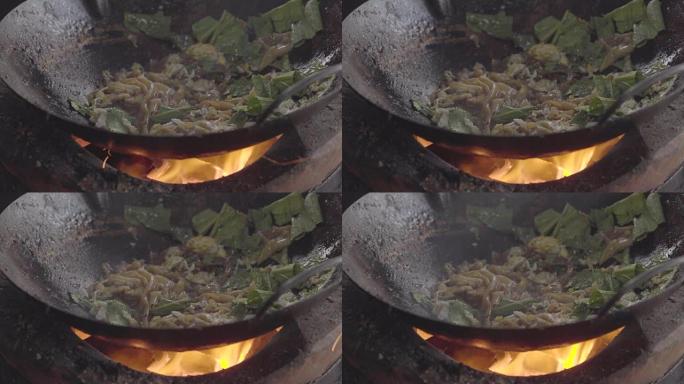 一个男人用炭炉做饭的电影镜头。用明火做的炒锅面条。泰国曼谷唐人街的街头美食
