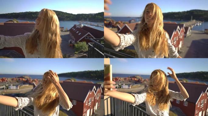 年轻的红发女人在北欧海岸的露台上给自己拍照
