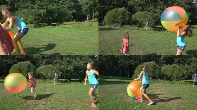 两个不同年龄的可爱的女孩玩一个巨大的彩色彩虹充气球。