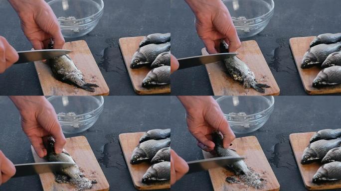 男人从木板上的鳞片上清洗鲤鱼。特写手。煮一条鱼。