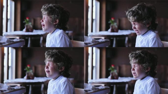 男孩在哭。心烦意乱的小孩在咖啡馆哭泣