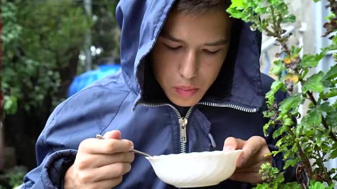 一个少年在雨中在外面吃饭