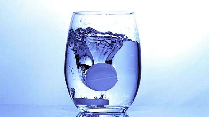 平板电脑在蓝色背景下落入一杯水中，慢动作