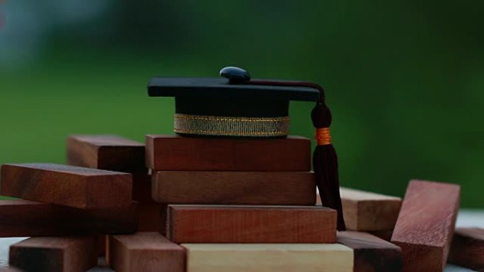 木制方形塔楼上的毕业庆祝帽。信件的空白，如教育、学习计划、毕业生等。出国商务国际教育的构想