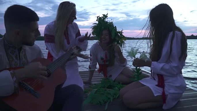 三个女孩和一个拿着吉他的男人坐在码头上