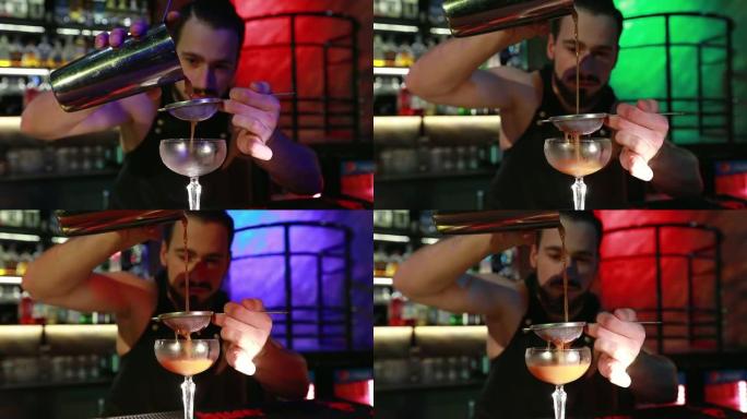大胡子的酒保将准备好的鸡尾酒倒入玻璃杯中。