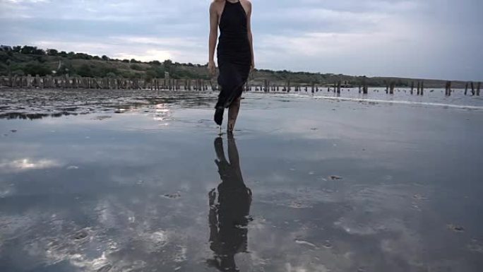 女人走在浅盐峡湾的平坦表面，身上有健康的黑泥。