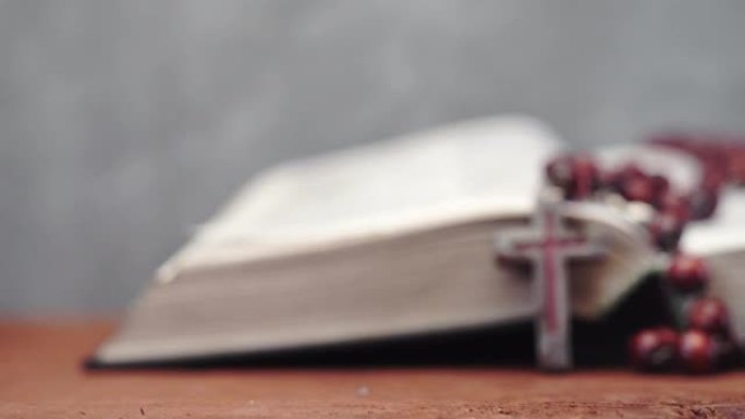 圣经和红色木桌上的耶稣受难像珠子。美丽的背景。宗教概念特写