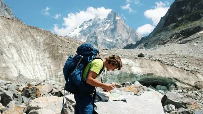 旅游指南一个背着背包的人在地图上研究路线，并在山上徒步旅行中打电话给GPS