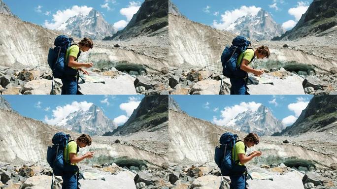 旅游指南一个背着背包的人在地图上研究路线，并在山上徒步旅行中打电话给GPS