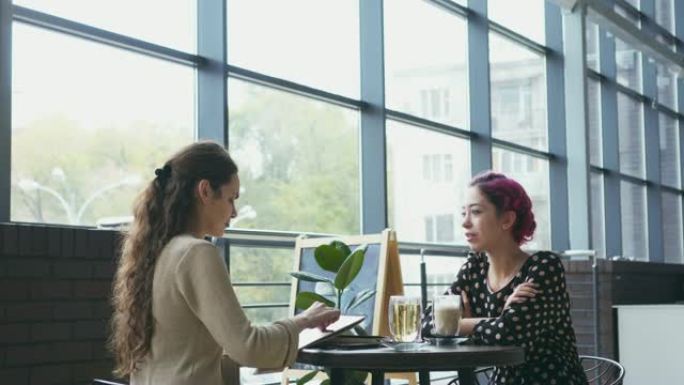 女人在咖啡馆画素描和与朋友聊天