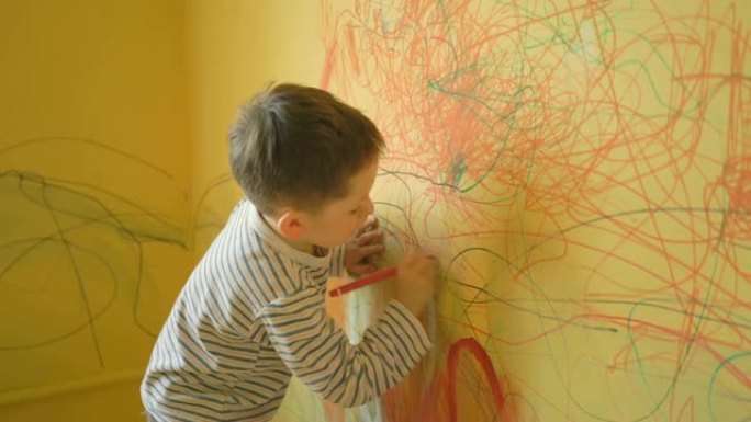 小男孩在家里的黄墙上画画