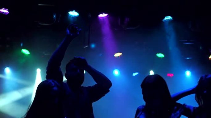 一群青少年在迪斯科舞厅跳舞，剪影。
