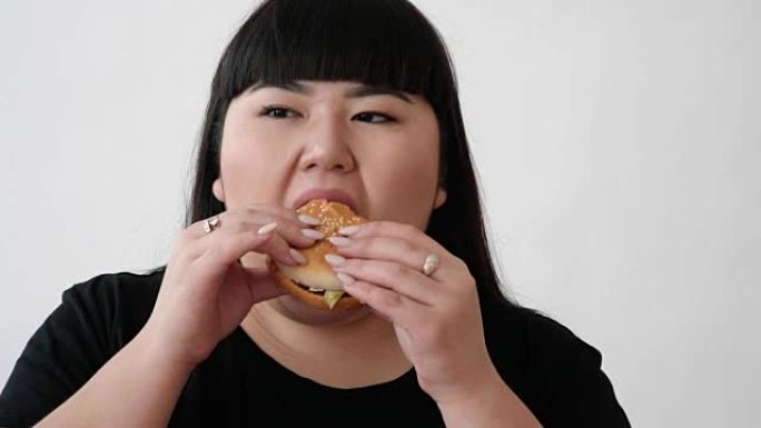 亚洲外表的女孩吃汉堡，享受味道。不是年轻人的健康饮食