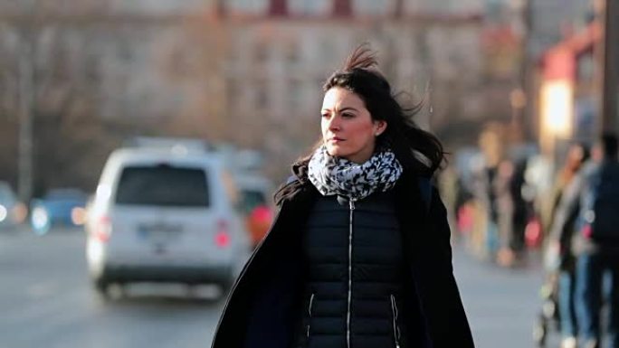 女人在寒冷的冬季日落时以4K 60fps慢动作走在城市人行道上