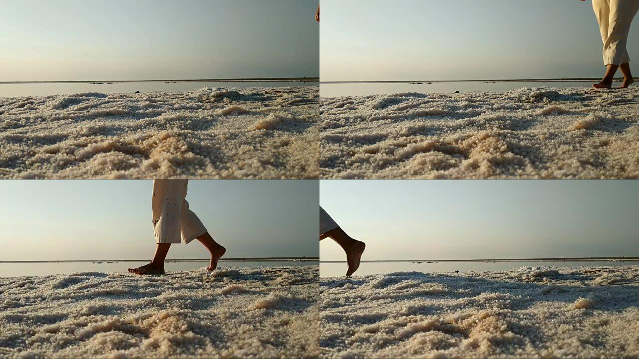 赤脚走在粉红湖盐岸的女孩。