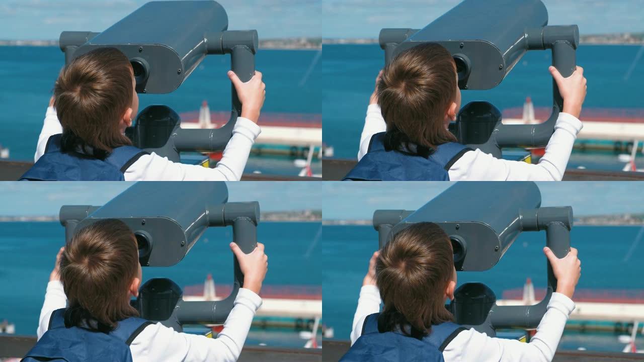 面目全非的男孩通过双筒望远镜看着大海。